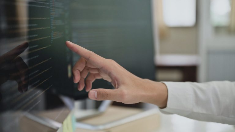 Close up shot of Programmers pointing fingers at the code on a computer screen.